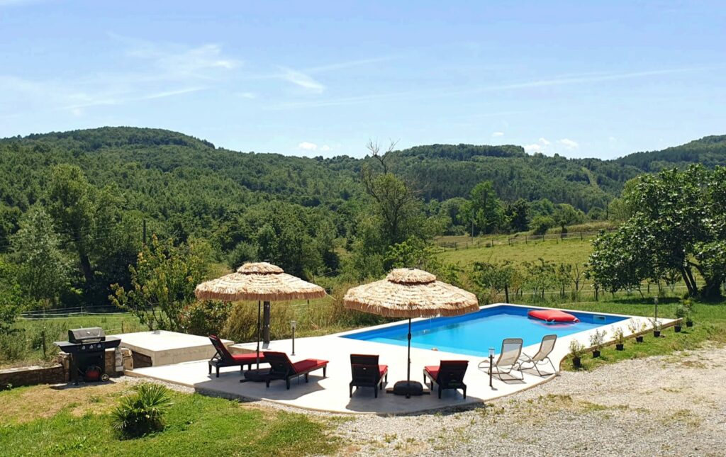 Vue du jardin, piscine, parasols, douche, barbecue, collines et champs