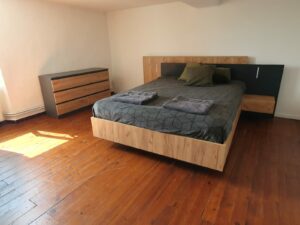 Chambre à l’étage du gîte en Ariège avec lit double, grande fenêtre et décoration boisée à Mirepoix
