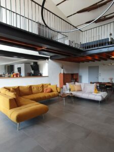 Salon du gîte en Ariège avec canapés confortables, décoration chaleureuse et grande luminosité naturelle à Mirepoix