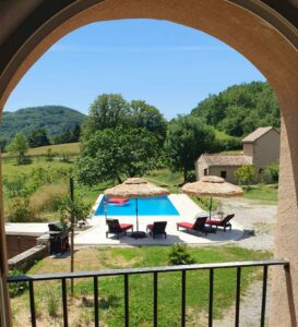 Vue extérieure sur la piscine et le jardin du Domaine Monbel prise depuis une fenêtre de la ferme en Ariège