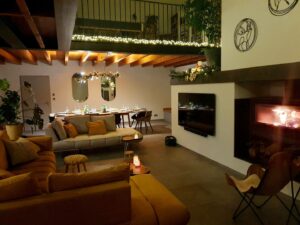 Salon du gîte en Ariège avec cheminée allumée, canapé confortable, TV et coin repas chaleureux à Mirepoix